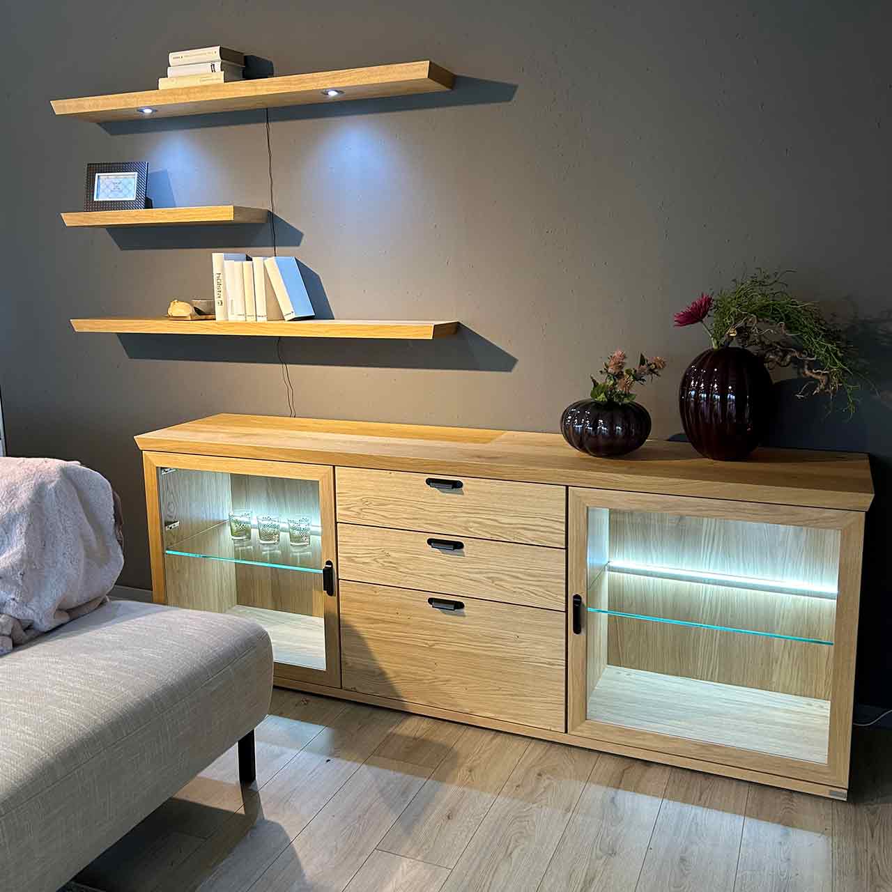 Sideboard-Kombination bestehend aus Sideboard und drei unterschiedlich langen Wandborden. Sideboard hat in der Mitte drei Schubladen und auf beiden Seiten Glastür mit Einlegeboden.