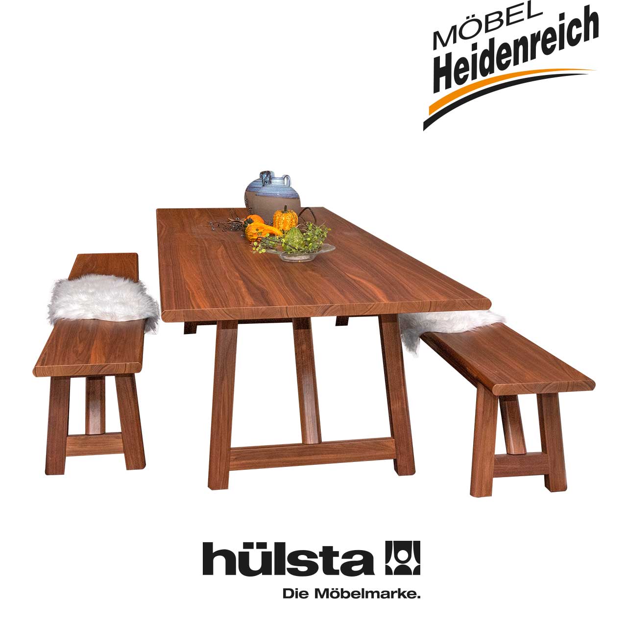 Tischgruppe aus dunklem Holz bestehend aus einem Tisch mit rechteckiger Tischplatte und drei Bänken ohne Lehne, eine lang, zwei kurz.