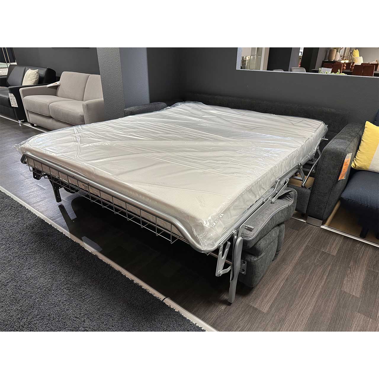 Ausgeklapptes Schlafsofa mit weißer Tempur-Matraze, die noch mit Schutz-Folie bezogen ist.