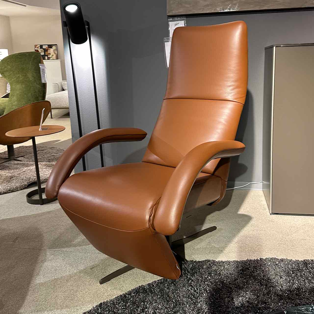 Leder-Sessel mit hoher Lehne aus braunem Leder mit bezogenen Armlehnen und Sternfuß.