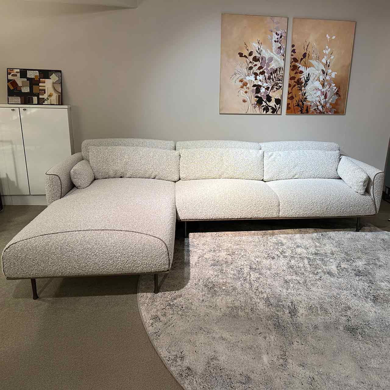 Modernes helles Ecksofa mit Ottomane links und beigem groben Stoffbezug.