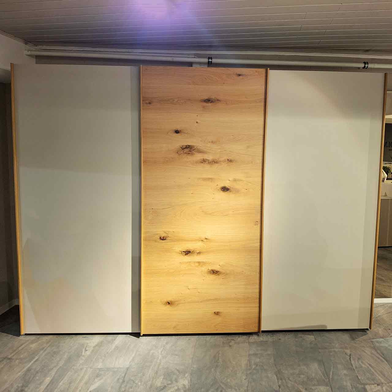 Schwebetürenschrank mit drei Türen, Fronten der Türen von links nach rechts: grauer Lack, Eiche mit Maserung, grauer Lack.