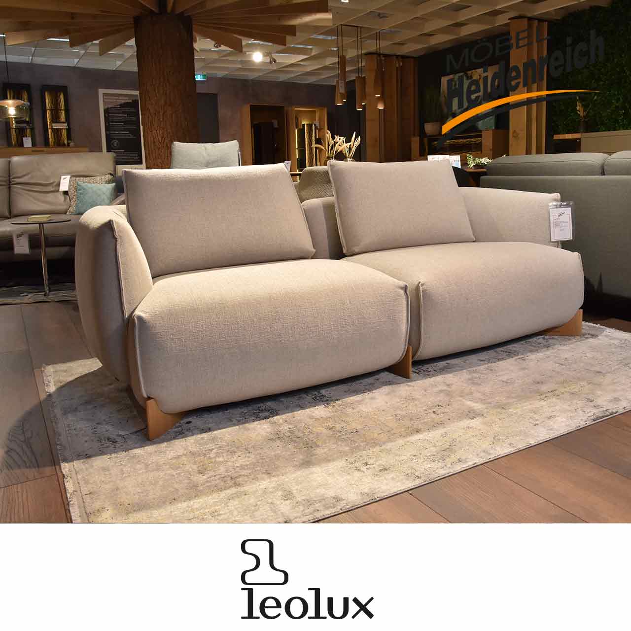 Graues Zweisitzer-Sofa mit zwei großen Rückenkissen und Holzfüßen.