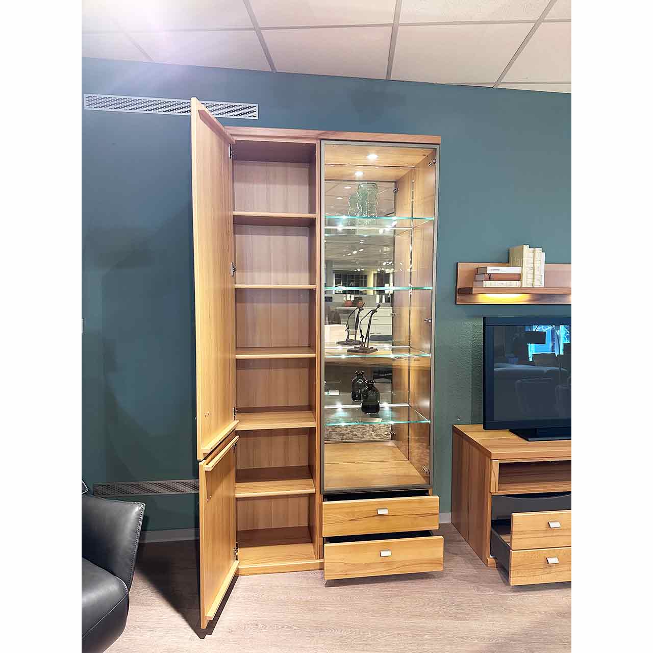 Der hohe Schrank mit geöffneter linker Holztür, dahinter 6 Fächer