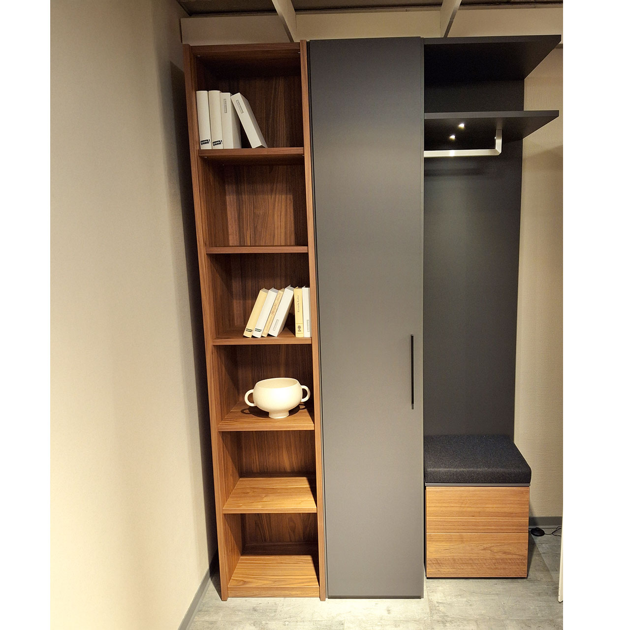 Loddenkemper - Garderobenschrank 3-teiliger Garderobenschrank mit offenem Regal in Kernnussbaum links, mittig Regalschrank mit Tür in grau und rechts mit Anstellregal mit Beleuchtung und Sitztruhe unten.