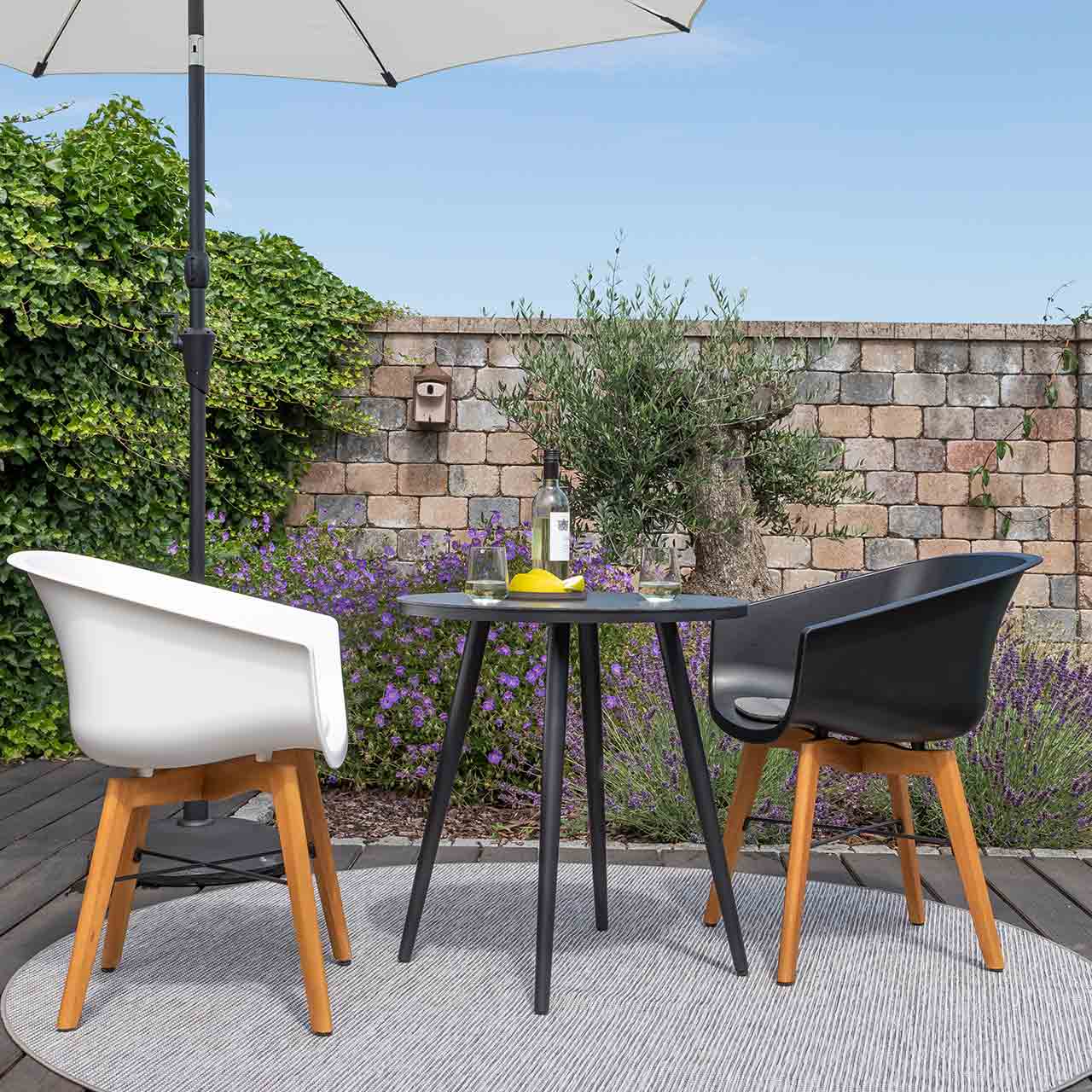 Gartengruppe Texel bestehend aus dem vierbeinigen runden Bistotisch mit schwarzer Glas-Keramik und Gartenstühle mit Kunstoffschale hier in weiß und schwarz kombiniert.