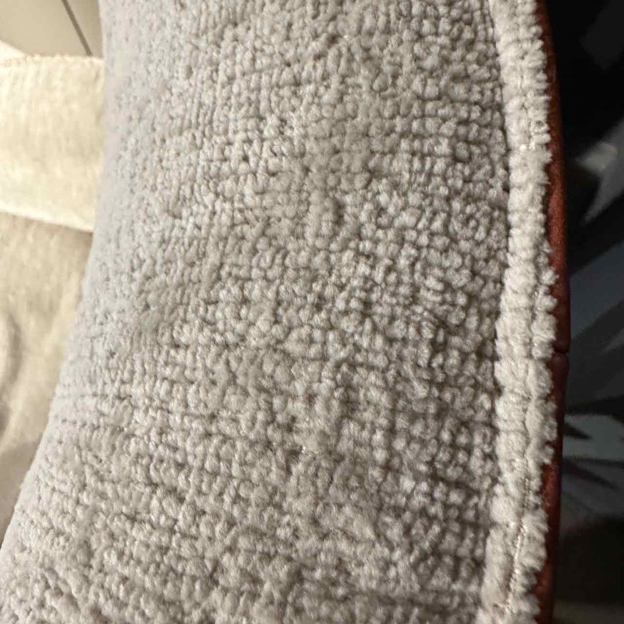 Detailaufnahme des kuscheligen hellen Stoffes an der Lehne.