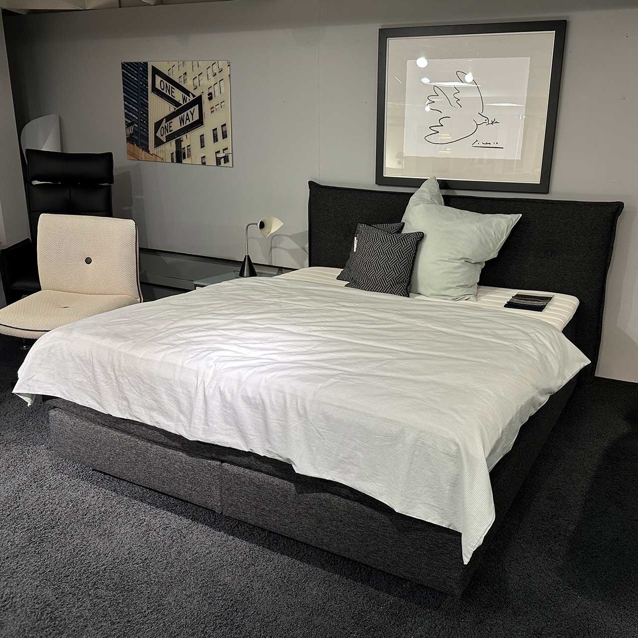 Femira - Boxspringbett Ando KT3 schwarz chwarzes Boxspringbett mit zwei Boxen unten und darüber zwei Matratzen in einer Hülle. Darauf liegt ein weißer Topper. Das Kopfteil in Kissenoptik ist hat jeweils zwei Knopf-Einzüge auf jeder Seite.