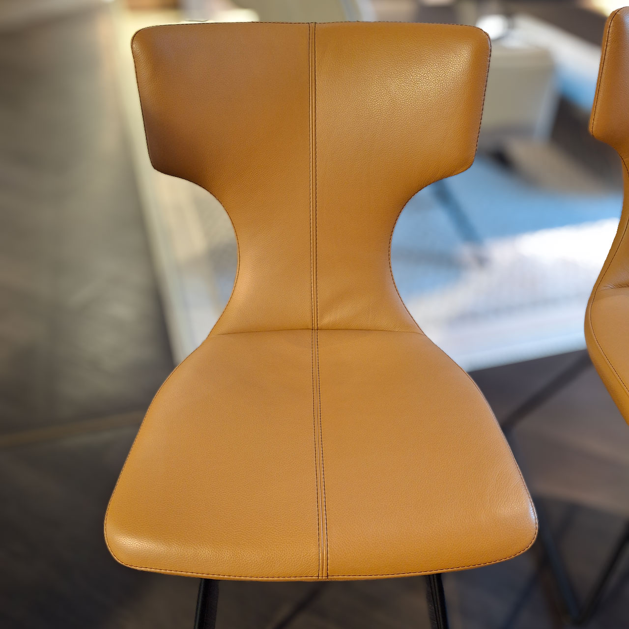Detailbild auf die Sitzfläche eines lederbezogenen Stuhls mit schwarzer Ziernaht.