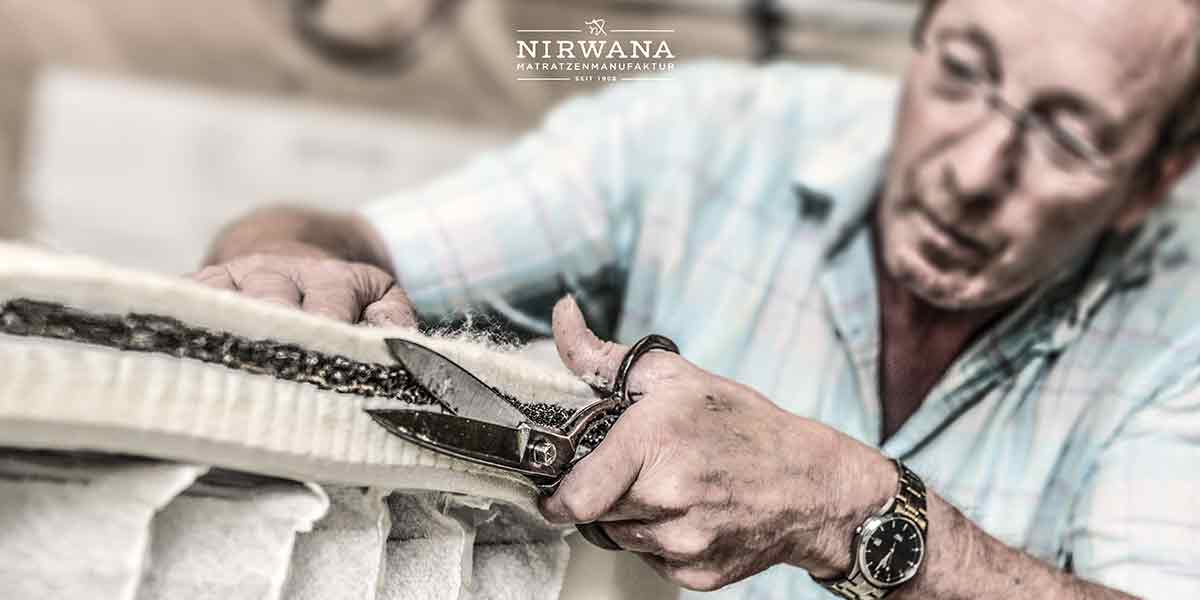 MH_Kategoriebanner_Nirwana Ein Blick hinter die Kulissen in der Fertigung von Produkten der Marke Nirwana, Man sieht einen Mann der mit einer Schere die Ränder einer Matratze zuschneidet.