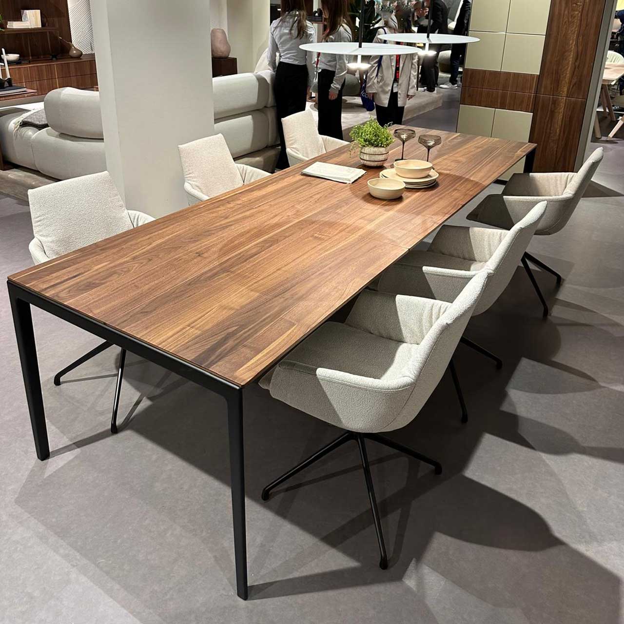 MH_Esszimmer_Essgruppe Das Bild zeigt eine Essgruppe mit sechs weißen Polsterstühlen an einem Tisch mit Naturholzplatte auf schwarzem Metallgestell.