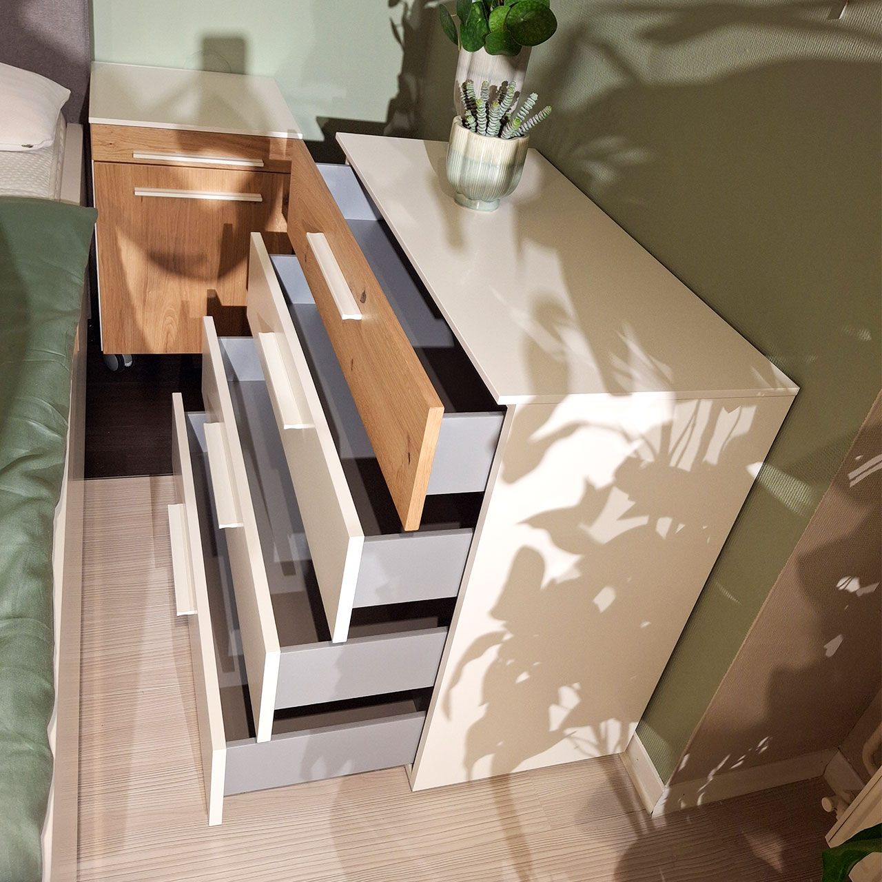 Loddenkemper - Kommode Seitenansicht auf eine Kommode mit vier Schubladen in weiß. Die oberste Schublade ist in Balkeneiche abgesetzt. Die Schubladen sind geöffnet.