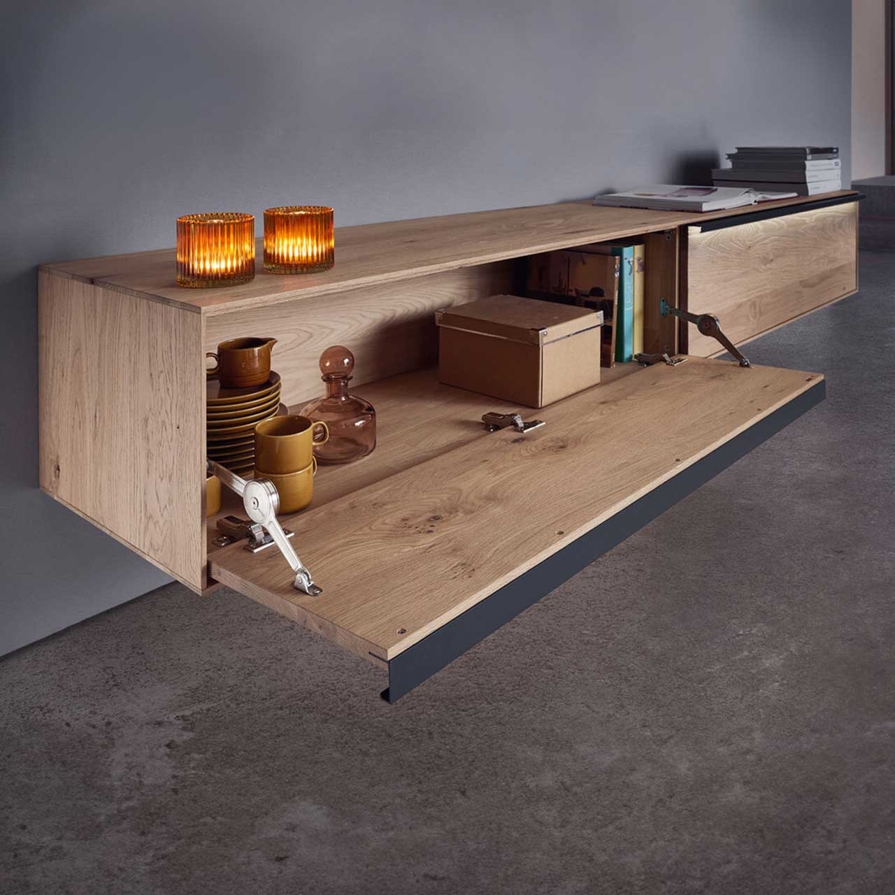 MH_Wohnzimmer_Lowboards Designerlowboard aus Holz auf einer Seite geöffnet mit Dekoelementen.