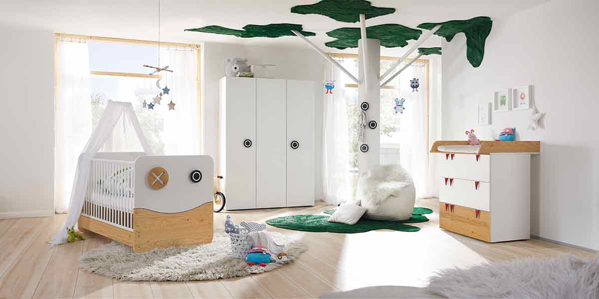 MH_Kategorie_Kinderzimmer Ambientebild lichtdurchflutetes Kinderzimmer in Weiß und Holzakzenten. Babybett mit Himmel, Kleiderschrank, Wickelkommode, gemütliche Teppiche und Dekoelemente.