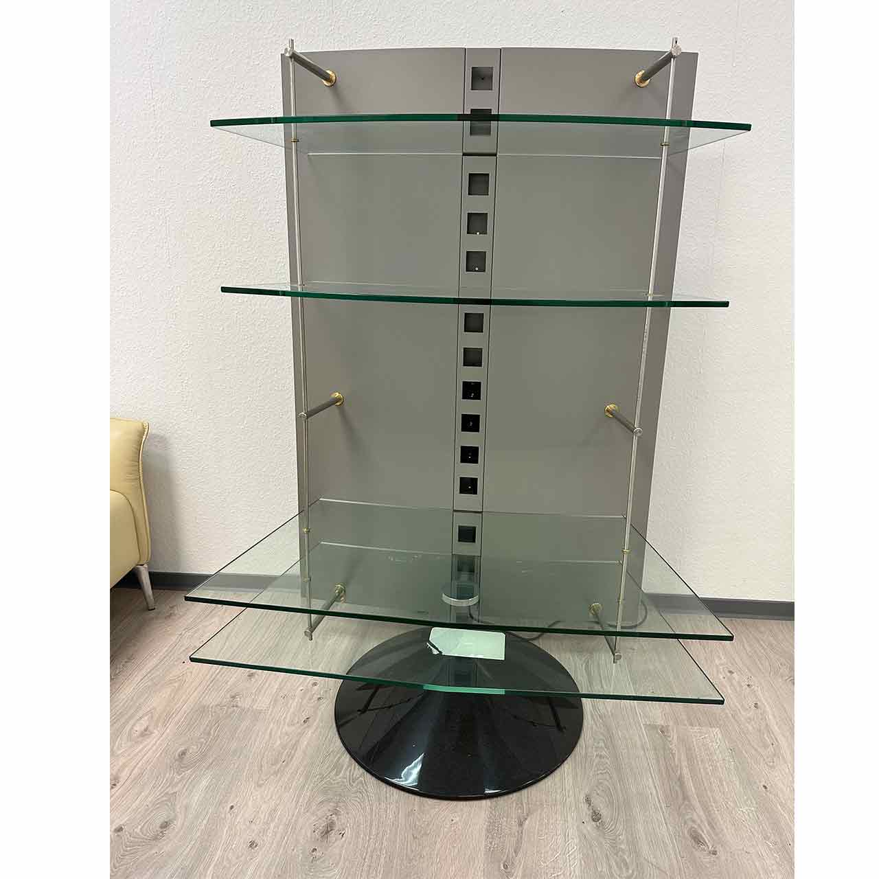 Regał mit silberfarbigem Rückenteil und schwarzem rundem Sockel mit vier Glasplatten.