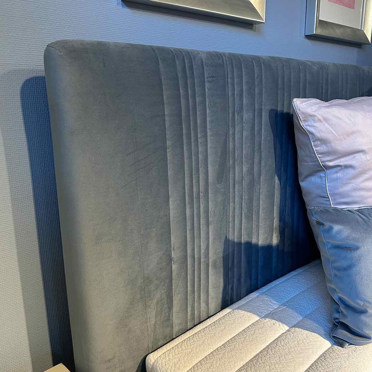 Detailaufnahme des hohen Kopfteils mit vertikalen Ziersteppungen im Stoff.