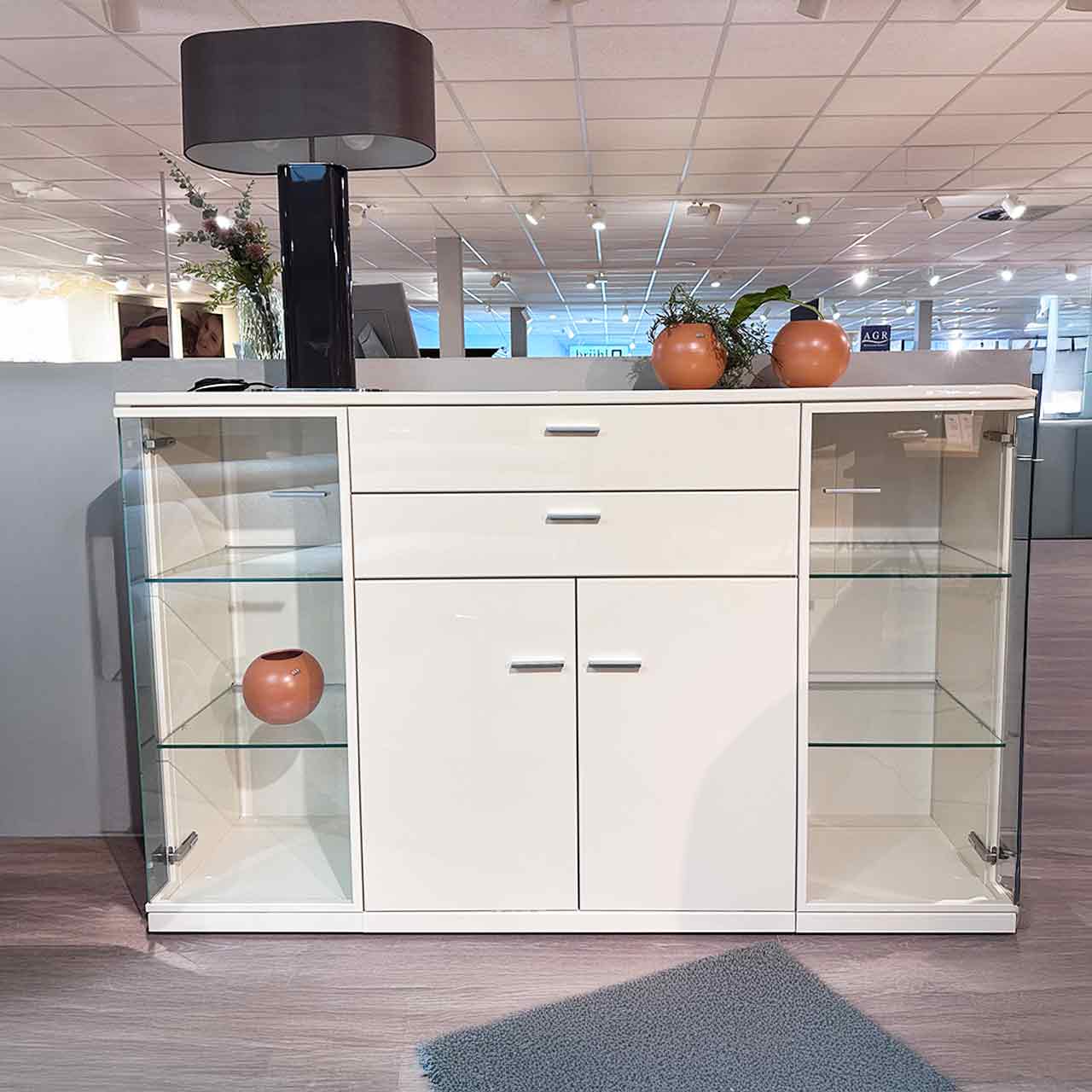 Cremefarbenes Highboard mit zwei Schubladen und daruter zwei Türen oben und an den Seiten je eine Glastür