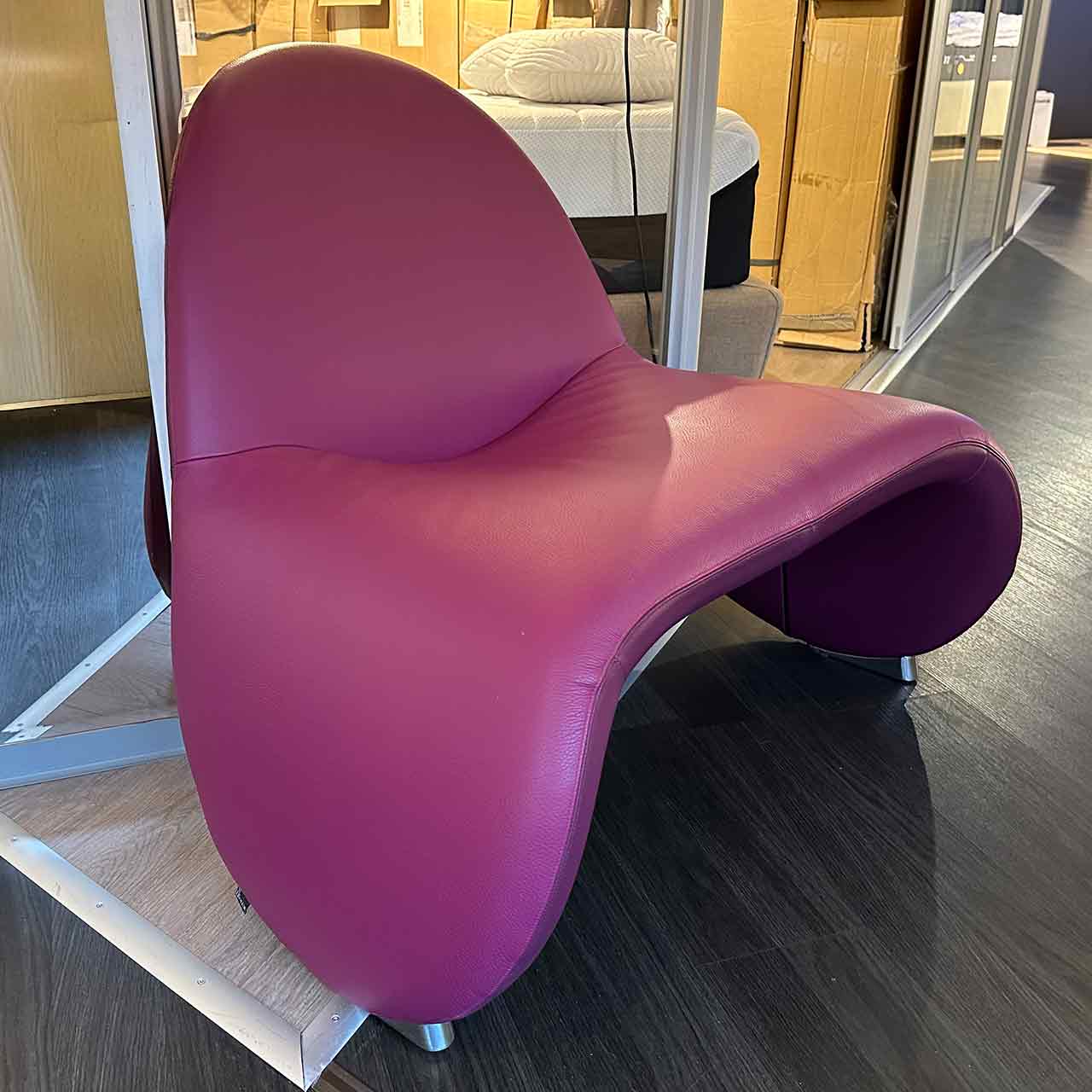 Der Sessel ist mit rotem Leder überzogen und die Armlehnen sind in U-Form nach unten gezogen.