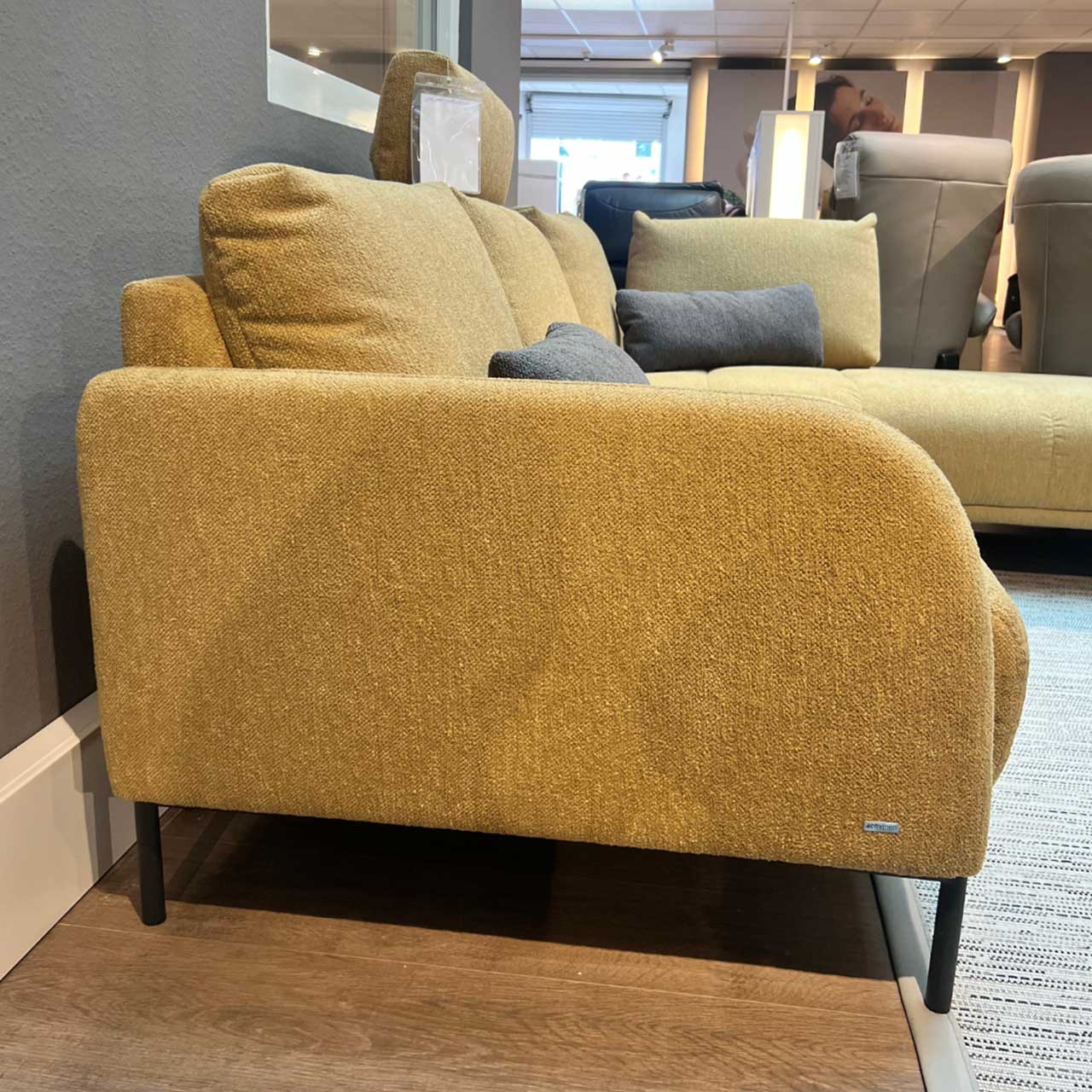 Gleiches Sofa von der Seite. Die vorne abgerundete Armlehne ist im Fokus.