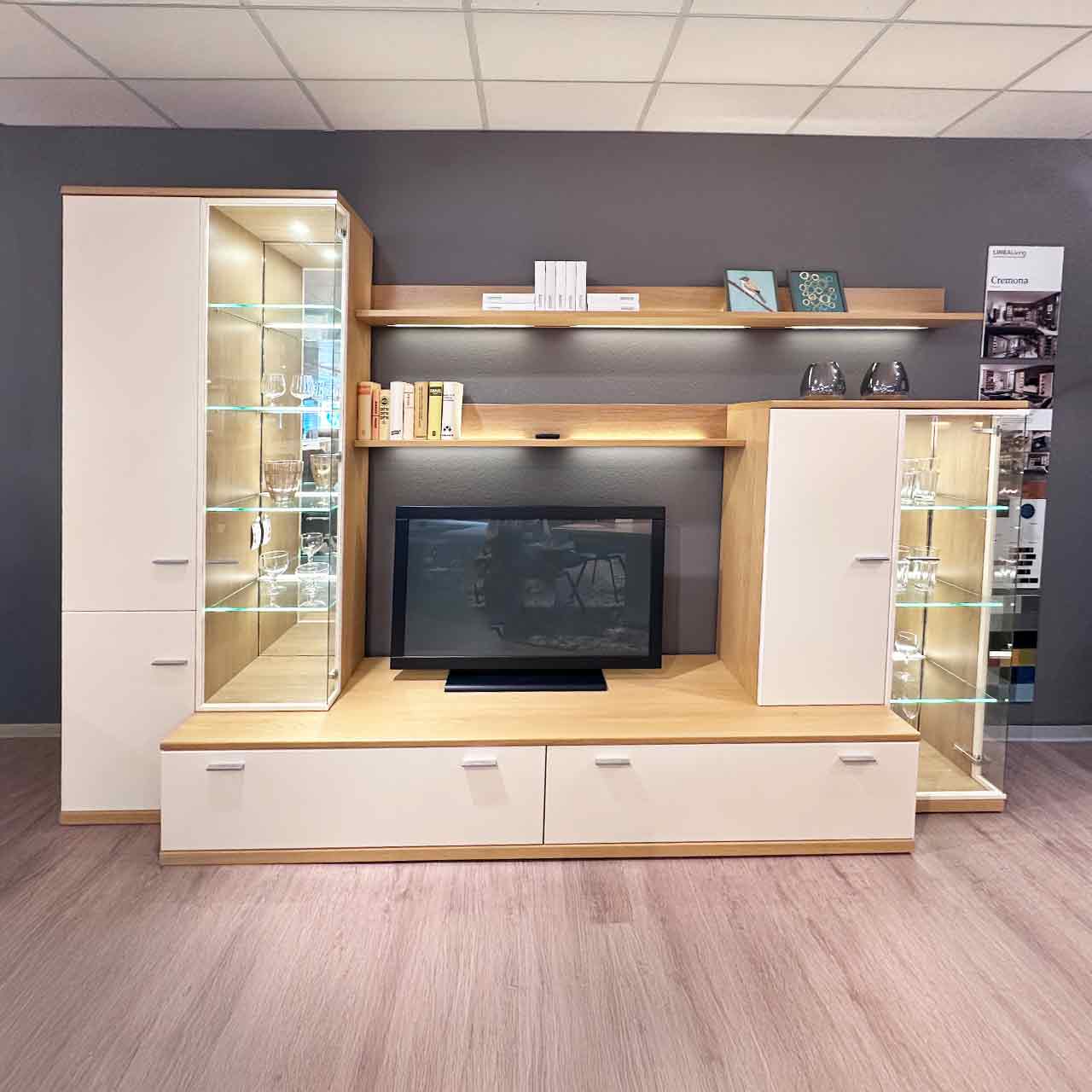 Wohnwand bestehend aus Vitrinenschrank links, Highboard rechts, beides steht zur Hälfte auf dem Lowboard. Darüber zwei Wandboarde.