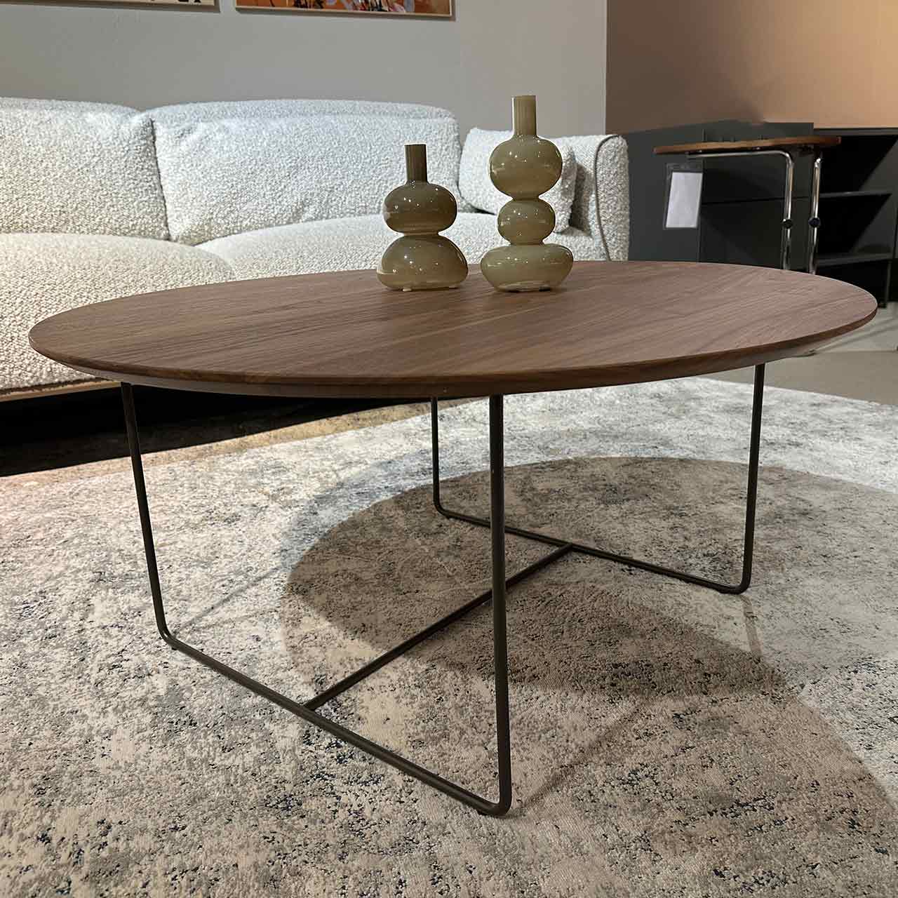 Couchtisch mit runder Holztischplatte auf bronzefarbenem filigranen Gestell.